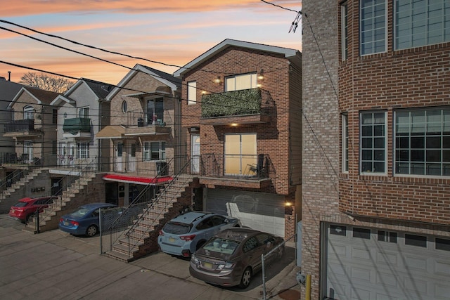 view of front of property featuring driveway, a garage, stairway, and brick siding