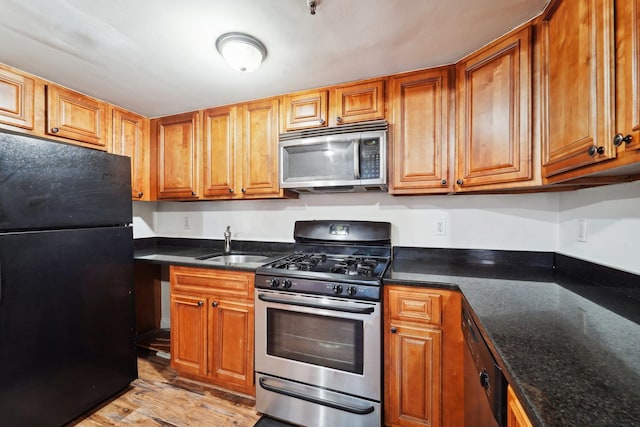 kitchen featuring black appliances, brown cabinetry, and a sink