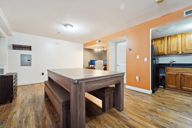 kitchen featuring electric panel, baseboards, wood finished floors, and freestanding refrigerator