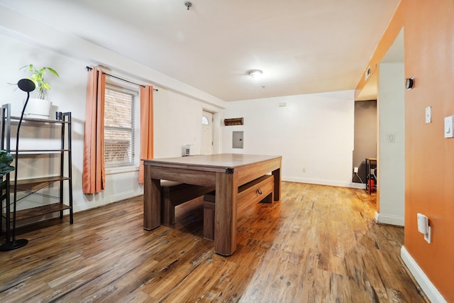 recreation room featuring electric panel, baseboards, and wood finished floors