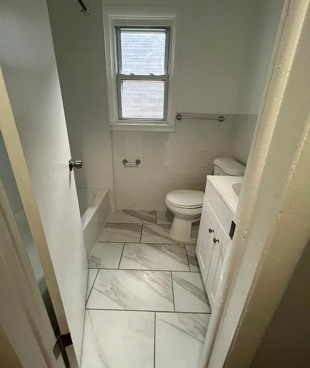 bathroom with toilet, a bathing tub, vanity, and tile walls