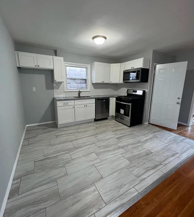 kitchen featuring white cabinets, backsplash, appliances with stainless steel finishes, and sink