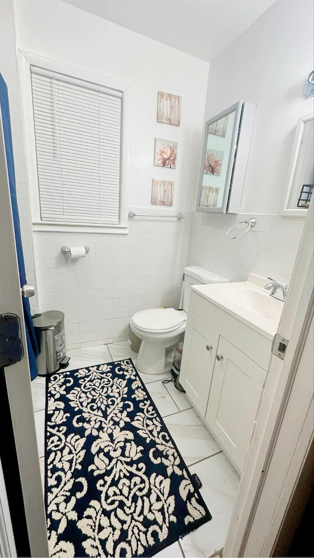 bathroom featuring toilet, vanity, and tile walls