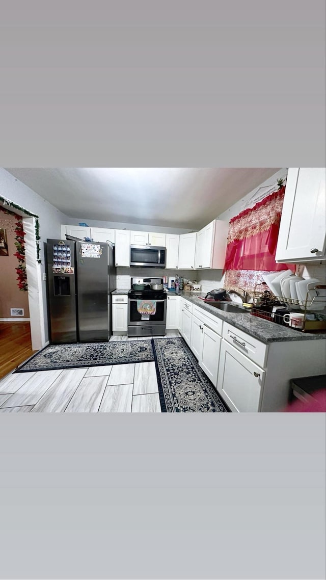 kitchen featuring sink, stainless steel appliances, white cabinetry, and kitchen peninsula