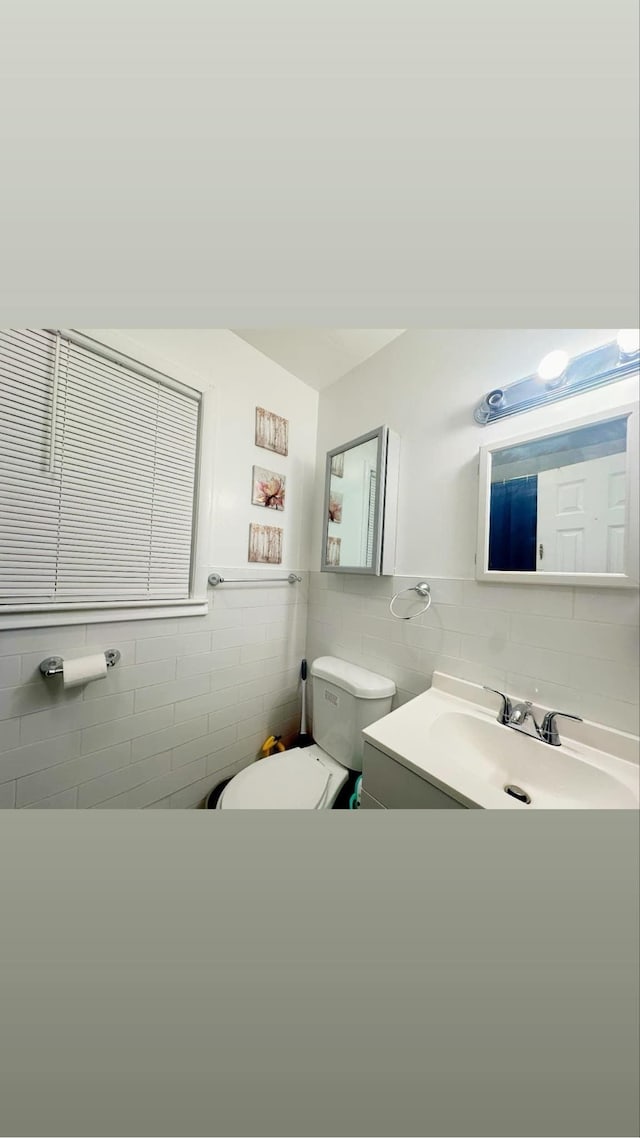 bathroom featuring vanity, toilet, and tile walls