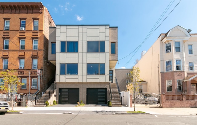 view of building exterior featuring stairs, fence, and a garage