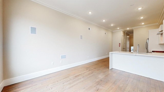 kitchen with light wood finished floors, white cabinets, crown molding, light countertops, and baseboards