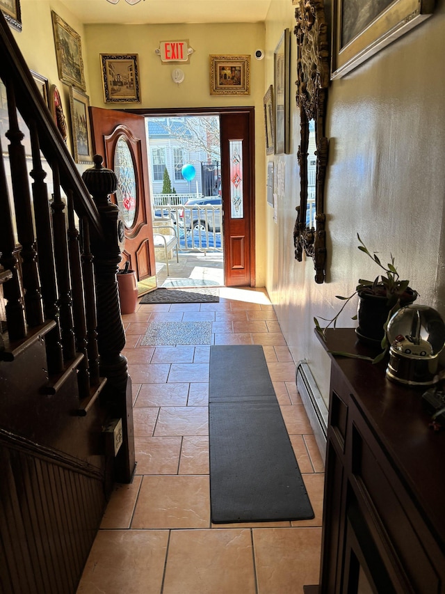 tiled foyer entrance featuring stairs and a baseboard heating unit