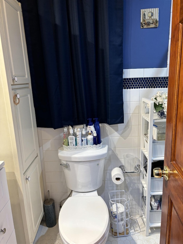 bathroom featuring tile patterned flooring, tile walls, and toilet