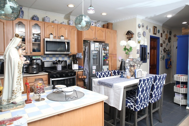 kitchen with dark tile patterned floors, ornamental molding, stainless steel appliances, light countertops, and glass insert cabinets