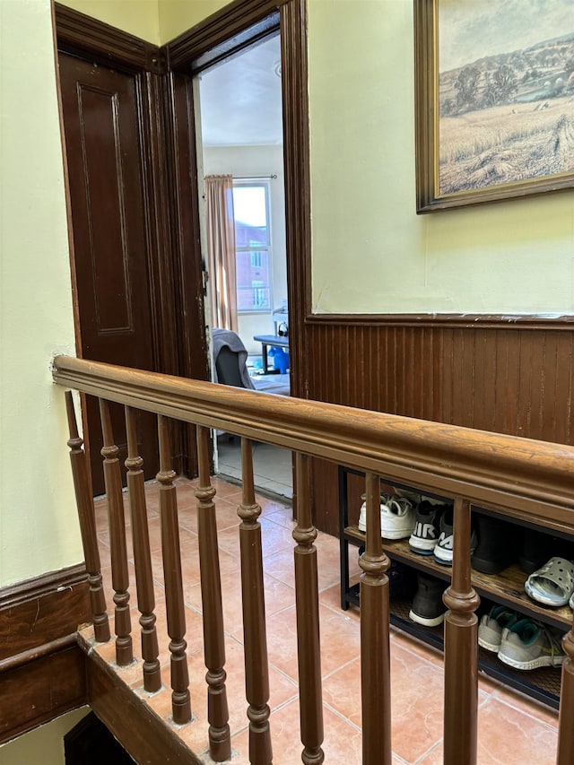 stairs with tile patterned flooring, wainscoting, and wood walls