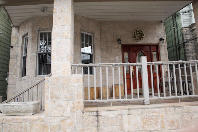 entrance to property featuring covered porch and stone siding