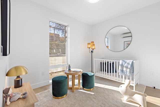 391 1st St Unit 3-B, Jersey City, NJ 07302 - bedroom featuring a wall mounted AC, a nursery area, baseboards, and wood finished floors