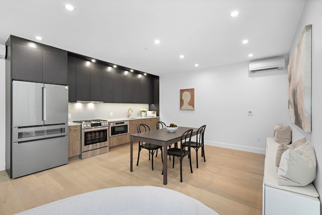 391 1st St Unit 3-B, Jersey City, NJ 07302 - kitchen with appliances with stainless steel finishes, a wall mounted air conditioner, dark cabinetry, light wood finished floors, and light countertops