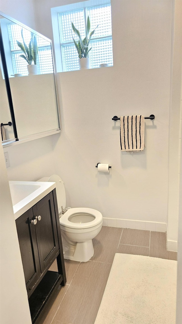 bathroom with vanity, baseboards, tile patterned floors, and toilet