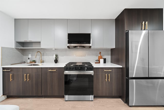 20 Storms Ave Unit 1A, Jersey City, NJ 07306 - kitchen featuring appliances with stainless steel finishes, light countertops, light wood-style flooring, decorative backsplash, and a sink