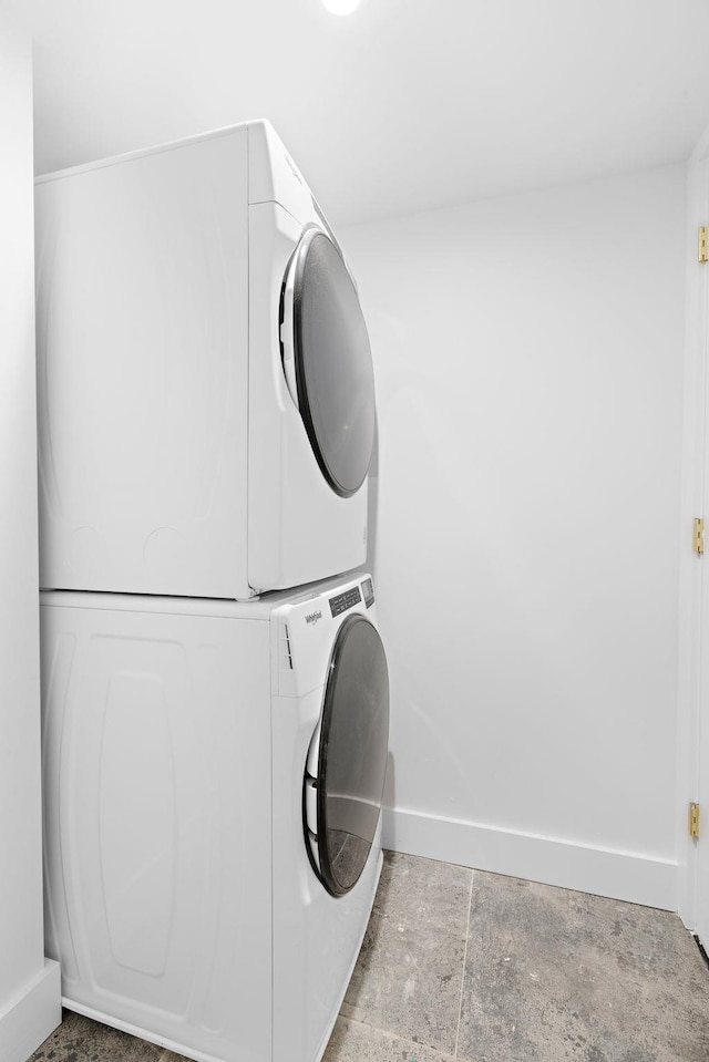 laundry room featuring stacked washer / drying machine, baseboards, and laundry area