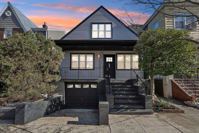 view of front facade featuring brick siding, a porch, stairs, driveway, and an attached garage