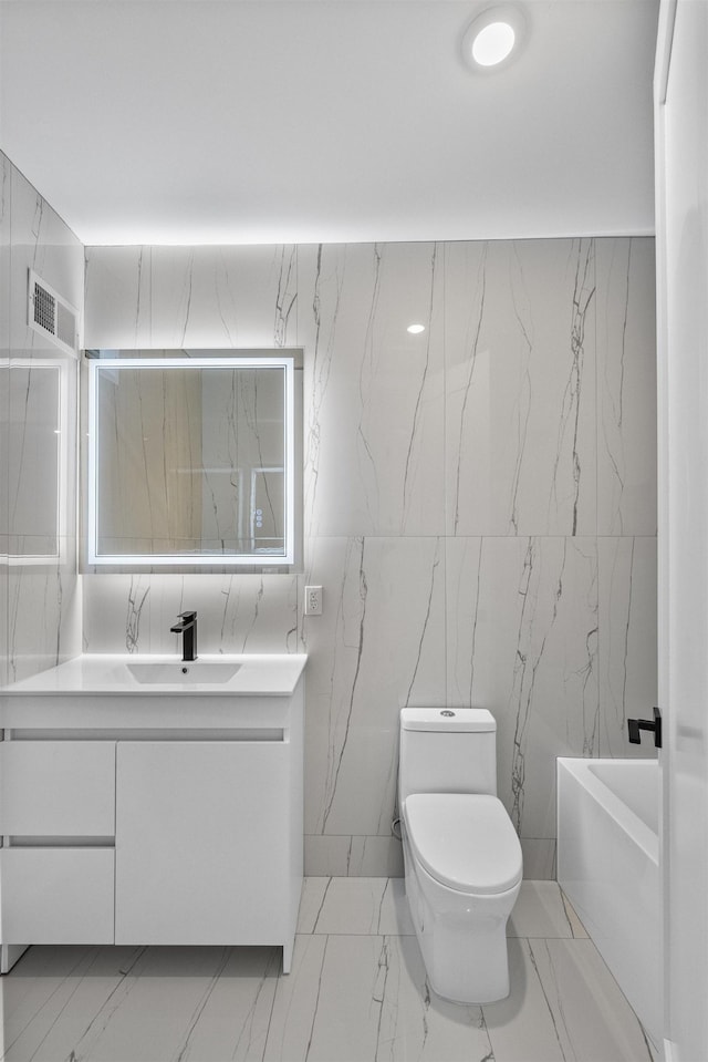 full bathroom with tile walls, marble finish flooring, toilet, vanity, and a bathtub