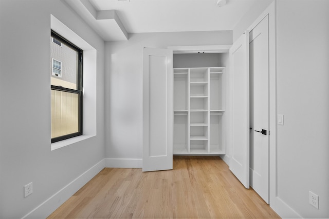 unfurnished bedroom with light wood-style floors, baseboards, and a closet