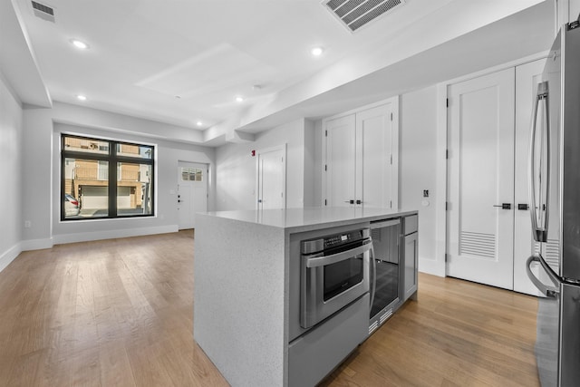 kitchen featuring stainless steel appliances, light wood-type flooring, recessed lighting, a kitchen island, and baseboards