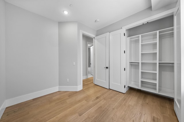unfurnished bedroom featuring baseboards, light wood-style floors, and a closet