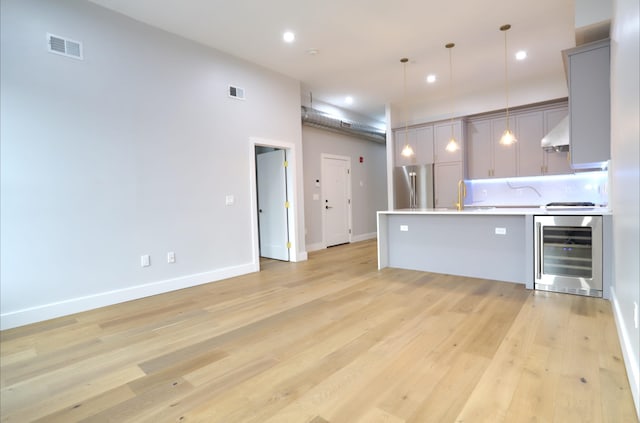 kitchen featuring high quality fridge, decorative light fixtures, gray cabinetry, wine cooler, and backsplash