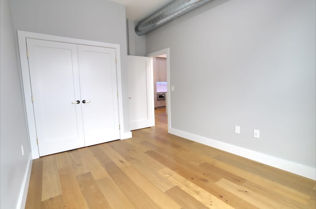 unfurnished bedroom featuring light hardwood / wood-style flooring and a closet