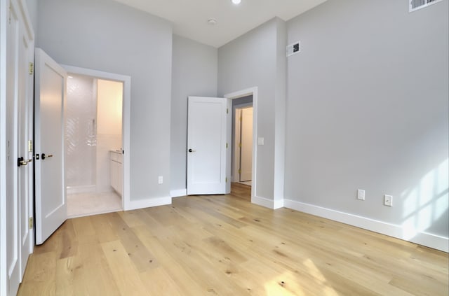 unfurnished bedroom featuring ensuite bath and light hardwood / wood-style flooring