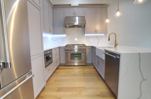 kitchen featuring pendant lighting, sink, gray cabinetry, exhaust hood, and stainless steel appliances