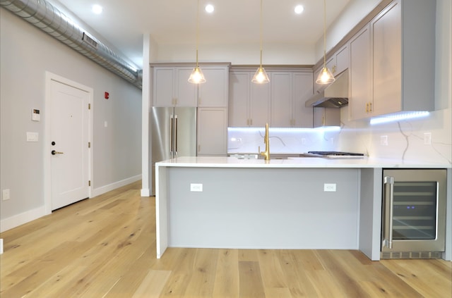 kitchen featuring gray cabinets, range hood, wine cooler, decorative light fixtures, and light wood-type flooring