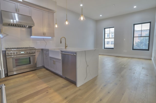 kitchen featuring sink, hanging light fixtures, backsplash, stainless steel appliances, and kitchen peninsula