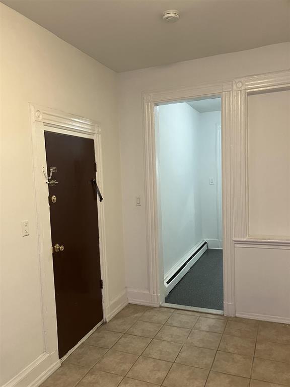 hallway with baseboard heating and light tile patterned floors