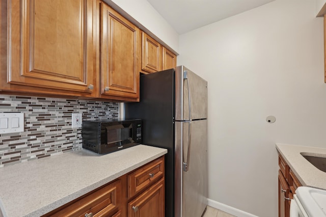 310 70th St Unit 1D, Guttenberg, NJ 07093 - kitchen with black microwave, backsplash, brown cabinetry, range, and baseboards