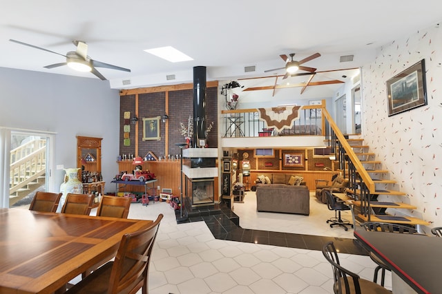 dining room featuring ceiling fan, a skylight, and a wood stove