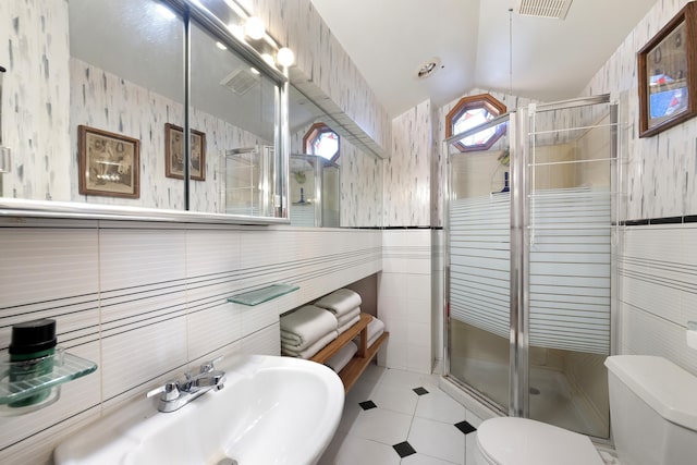 bathroom featuring toilet, a shower with shower door, sink, vaulted ceiling, and tile walls