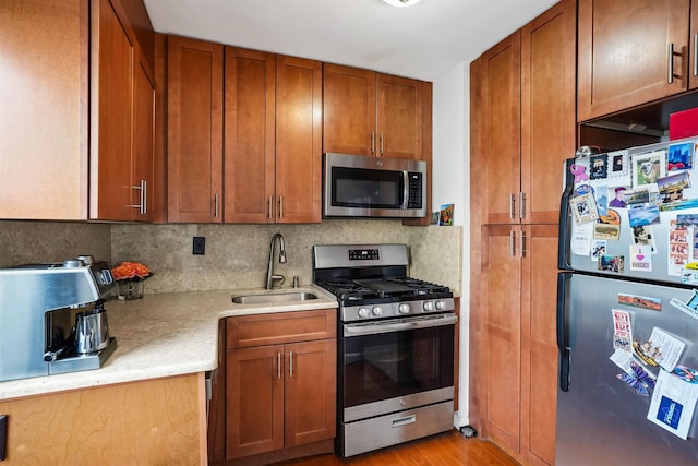 kitchen with light countertops, stainless steel appliances, decorative backsplash, and a sink