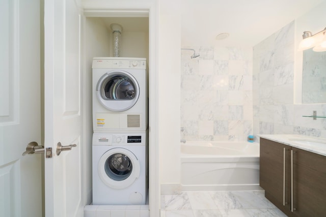 laundry area featuring marble finish floor, stacked washer / dryer, a sink, and laundry area