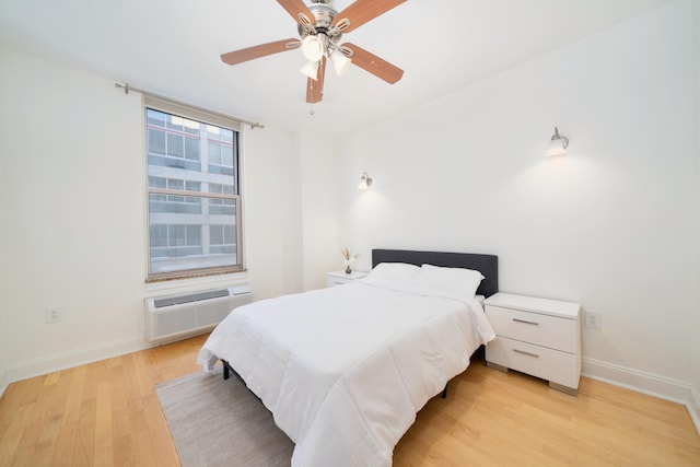 bedroom featuring a ceiling fan, light wood-type flooring, baseboards, and a wall mounted AC