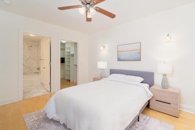 bedroom with a walk in closet, a closet, baseboards, and light wood finished floors