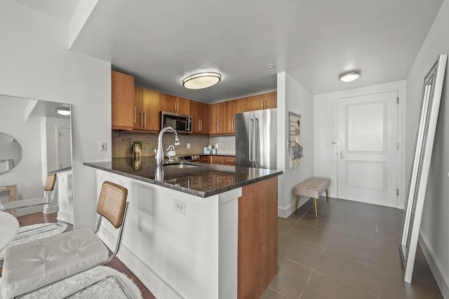 88 Morgan St Unit 4306, Jersey City, NJ 07302 - kitchen featuring stainless steel appliances, brown cabinetry, a peninsula, and baseboards