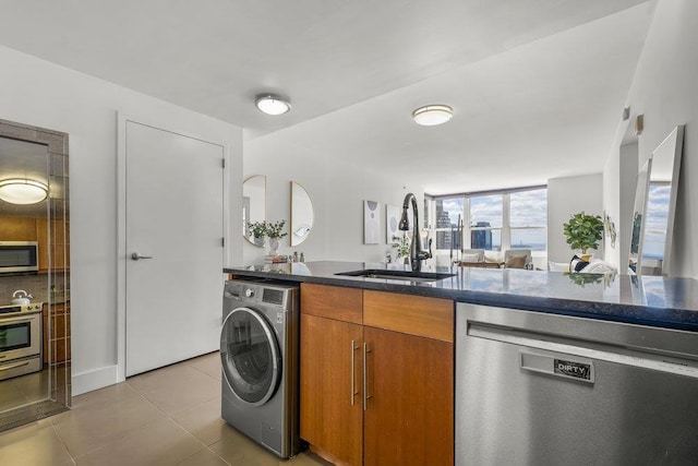 88 Morgan St Unit 4306, Jersey City, NJ 07302 - kitchen featuring appliances with stainless steel finishes, washer / clothes dryer, a sink, brown cabinets, and tile patterned flooring