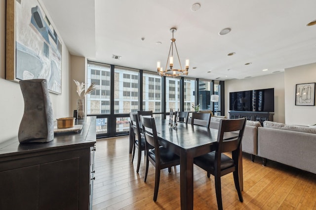 dining space featuring light wood-style floors, visible vents, expansive windows, and a chandelier