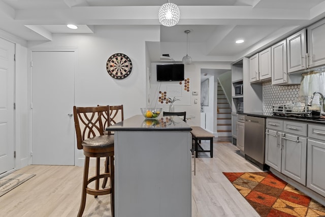 kitchen featuring gray cabinetry, stainless steel dishwasher, a breakfast bar, and a center island