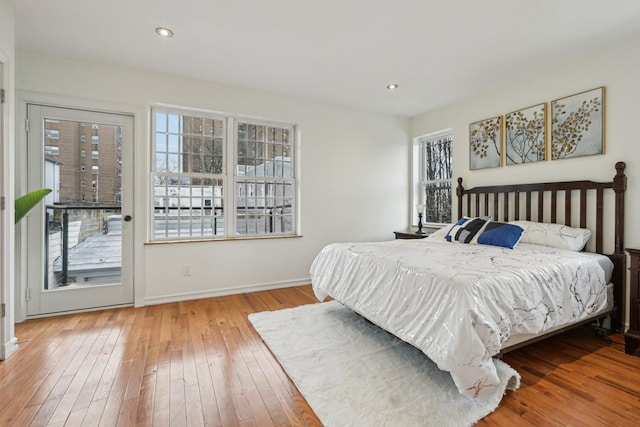 bedroom with multiple windows, access to outside, hardwood / wood-style floors, baseboards, and recessed lighting