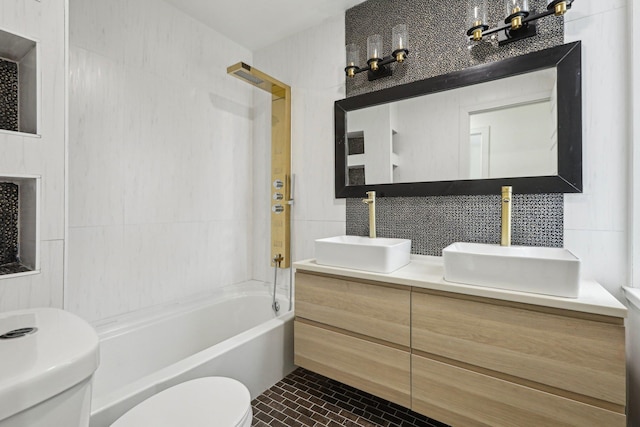 bathroom featuring toilet, tile walls, decorative backsplash, shower / bath combination, and double vanity