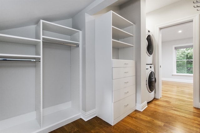 spacious closet featuring stacked washer / drying machine and wood finished floors