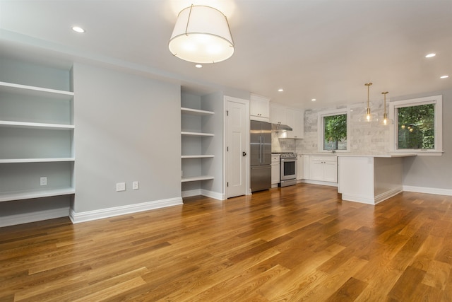 unfurnished living room featuring recessed lighting, wood finished floors, and baseboards