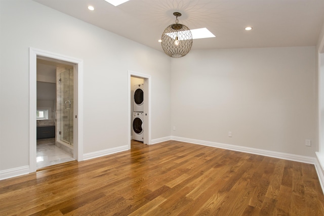 spare room featuring recessed lighting, a skylight, stacked washer / drying machine, and wood finished floors