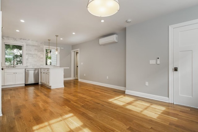 unfurnished living room featuring light wood finished floors, recessed lighting, a wall mounted air conditioner, and baseboards